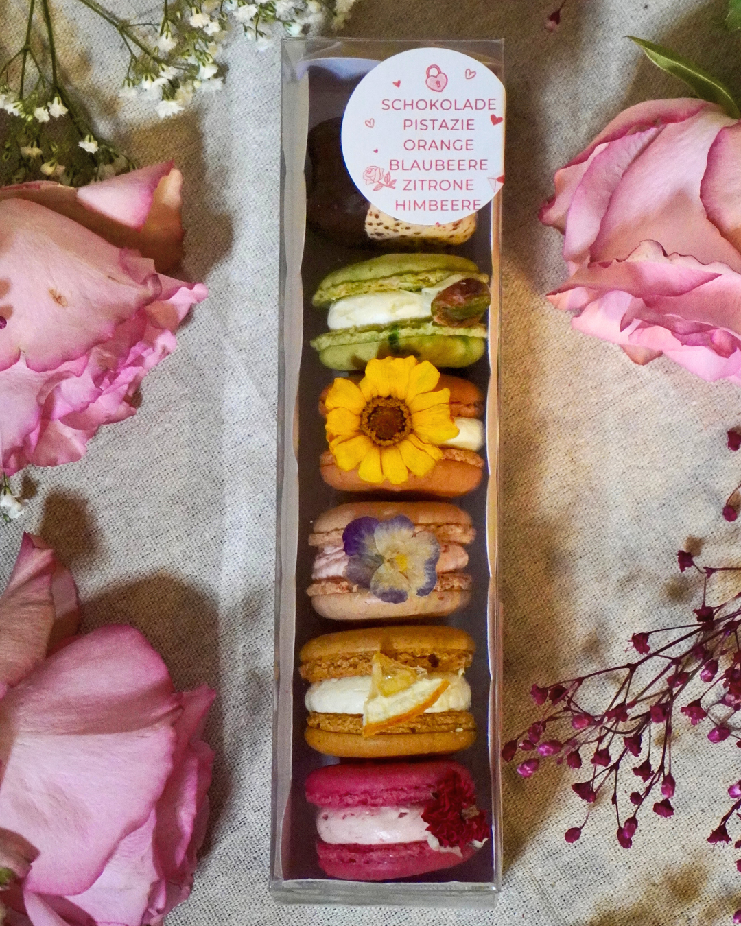 Eine dekorative Schachtel mit Makronen, umgeben von frischen Blumen