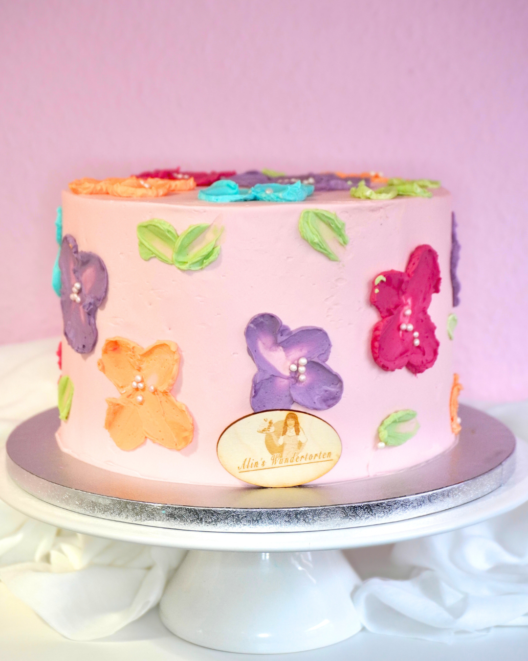 Ein rosa Kuchen, verziert mit farbenfrohen Blumen, der eine fröhliche und festliche Stimmung vermittelt